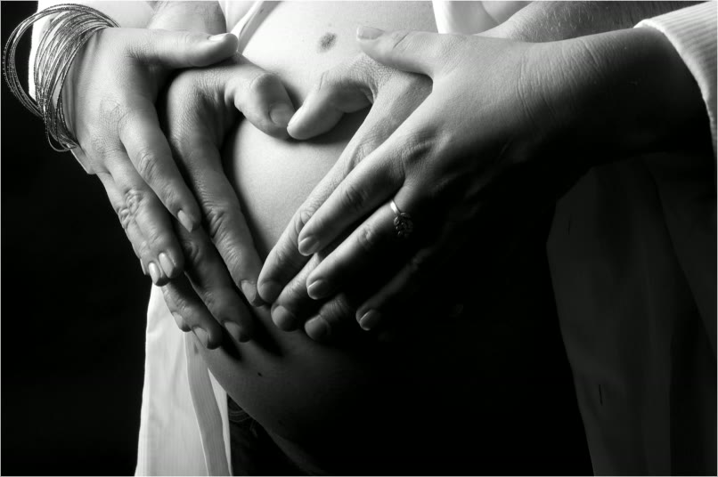 Hände formen ein Herz auf dem Babybauch
